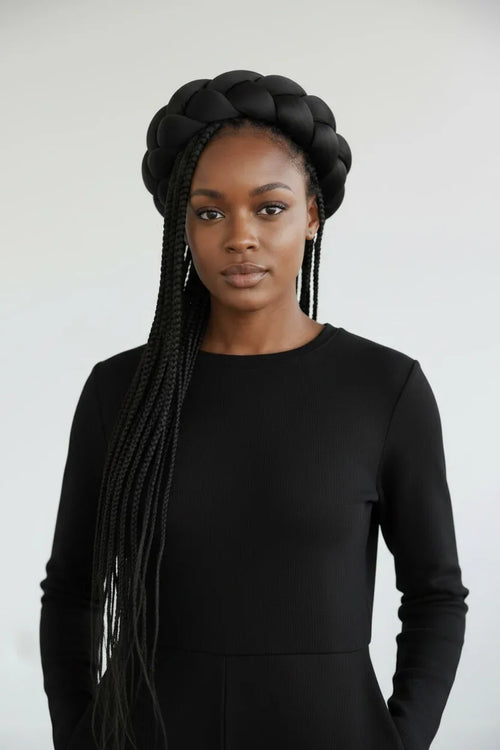 Woman with braided hair wearing a black outfit against a white background