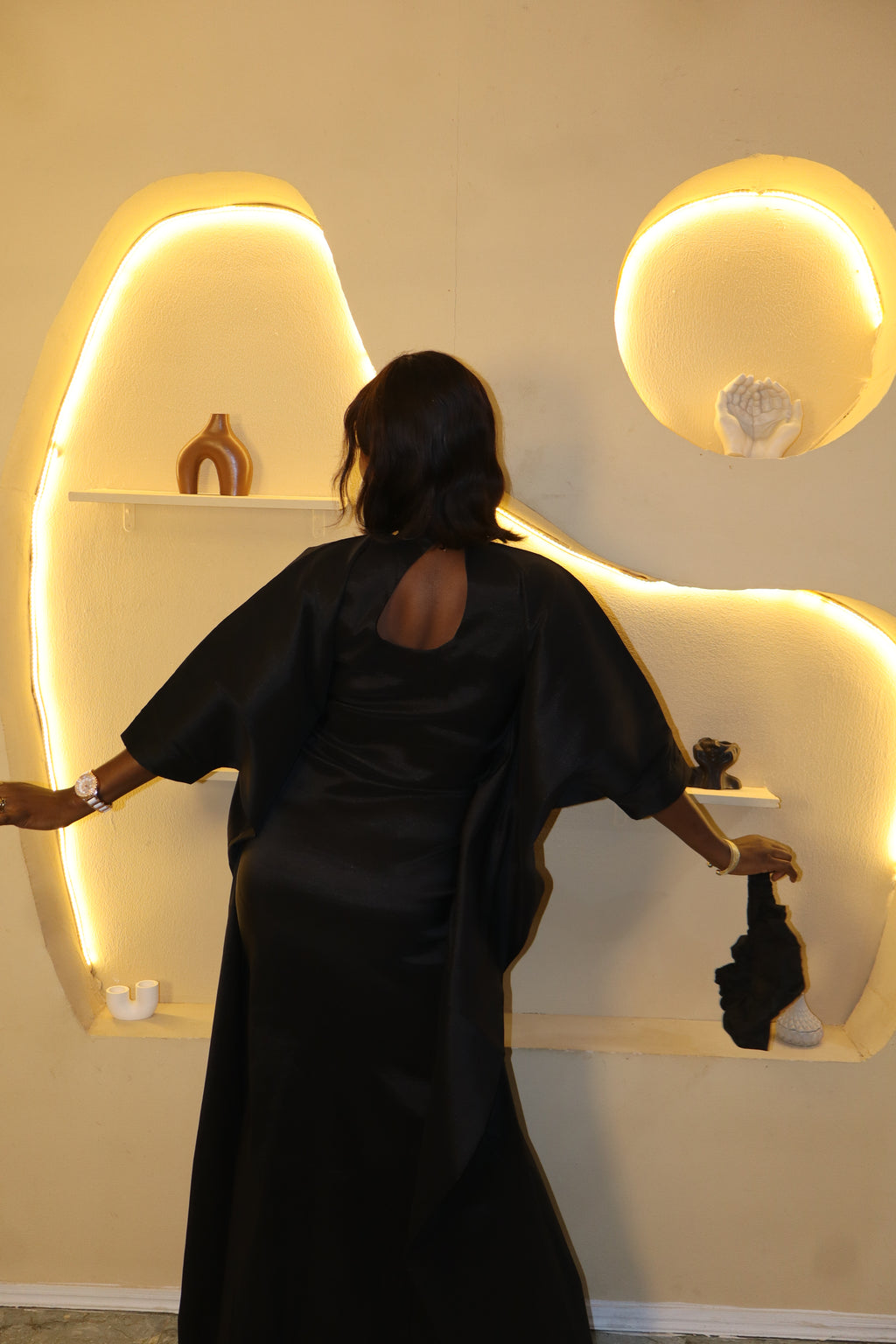 Woman wearing a black dress standing in front of a decorative wall with illuminated arches.